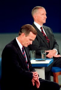 FILE - In this Oct. 15, 1992, file photo President George H.W. Bush looks at his watch during the 1992 presidential campaign debate with other candidates, Independent Ross Perot, top, and Democrat Bill Clinton, at the University of Richmond, Va. For presidential candidates, the town hall debate is a test of stagecraft as much as substance. When Hillary Clinton and Donald Trump meet in the Sunday, Oct.9, 2016, contest, they’ll be fielding questions from undecided voters seated nearby. In an added dose of unpredictability, the format allows the candidates to move around the stage, putting them in unusually close proximity to each other. (AP Photo/Ron Edmonds, File)