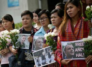 Supporters hold flowers and and placards as the British human rights activist Andy Hall arrives at Bangkok South Criminal Court for his verdict on criminal and civil defamation cases filed against him, in Bangkok, Thailand Tuesday, Sept. 20, 2016. Bangkok South Criminal Court found Hall guilty Tuesday of criminal defamation against Natural Fruit Company Ltd. in connection with a report he researched for the Finnish consumer agency Finnwatch that alleged labor abuses at the company's facilities. (AP Photo/Sakchai Lalit)