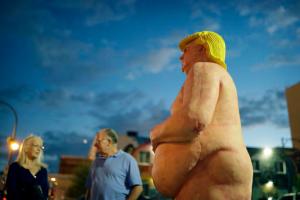 In this Sept. 21, 2016, photo, people look at a statue of a naked Republican presidential candidate Donald Trump in Las Vegas. The statue was knocked down and sprayed with graffiti overnight, and removed Friday, Sept. 23. (AP Photo/John Locher)