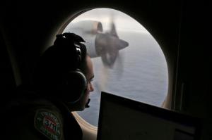 FILE - In this March 22, 2014 file photo, flight officer Rayan Gharazeddine scans the water in the southern Indian Ocean off Australia from a Royal Australian Air Force AP-3C Orion during a search for the missing Malaysia Airlines Flight MH370. A ship involved with the deep-sea sonar search for missing Malaysia Airlines Flight 370 is being fitted with equipment to examine several sonar contacts of interest on the remote seabed west of Australia, the Australian Transport Safety Bureau said on Wednesday, Oct. 19, 2016. (AP Photo/Rob Griffith, File)