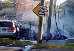 Smoke pours from the smoldering remains of a small plane that crashed on Main Street in East Hartford Conn., Tuesday, Oct. 11, 2016. Authorities said at least one person is dead and another is injured after a small airplane crashed near the Connecticut River. (Jim Michaud/Journal Inquirer via AP)