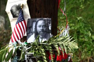FILE – In this July 29, 2015, file photo, photos of Sam DuBose hang on a pole at a memorial near where he was shot and killed by a University of Cincinnati police officer during a July 19, 2015, traffic stop in Cincinnati. Former University of Cincinnati police officer Ray Tensing, facing trial on charges of murder and voluntary manslaughter, was due back in court for a Friday, Oct. 14, 2016, pretrial hearing, ahead of the planned start of jury selection on Oct. 25, 2016. (AP Photo/Tom Uhlman, File)