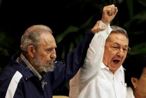 FILE - In this April 19, 2011 file photo, Fidel Castro, left, raises his brother's hand, Cuba's President Raul Castro, center, as they sing the anthem of international socialism during the 6th Communist Party Congress in Havana, Cuba. Cuban President Raul Castro has announced the death of his brother Fidel Castro at age 90 on Cuban state media on Friday, Nov. 25, 2016. (AP Photo/Javier Galeano, File)