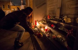 A woman places a candle in front of the home of singer and poet Leonard Cohen, Thursday, Nov. 10, 2016 in Montreal. Cohen, the baritone-voiced Canadian singer-songwriter who seamlessly blended spirituality and sexuality in songs like "Hallelujah," "Suzanne" and "Bird on a Wire," has died at age 82.  (Paul Chiasson/The Canadian Press via AP)