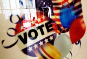 In this Nov. 1, 2016, photo, a voter is reflected in the glass frame of a poster while leaving a polling site during early voting ahead of next week's election in Atlanta. Hillary Clinton may not be accumulating the type of early-vote advantage her campaign wanted, but she continues to maintain an apparent edge over Donald Trump, with roughly one-fourth of all expected ballots cast in the 2016 election. (AP Photo/David Goldman)