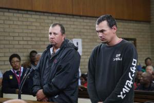 Theo Jackson, left, and Willem Oosthuizen, right, appear in the Magistrates Court in Middelburg, South Africa Wednesday, Nov. 16, 2016. Two white South Africans accused of forcing a black man into a coffin and threatening to set him on fire appeared before a judge on Wednesday as demonstrators protested against racism outside the courthouse. (AP Photo)