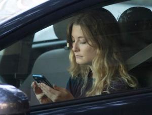 FILE - In this Wednesday, June 22, 2016, file photo, a driver uses her mobile phone while sitting in traffic in Sacramento, Calif. The government wants smartphone makers to lock out most apps when the phone is being used by someone driving a car. The voluntary guidelines unveiled Wednesday, Nov. 23, 2016, are designed to reduce crashes caused by drivers distracted by phones. (AP Photo/Rich Pedroncelli, File)
