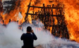 A photographer takes pictures of a pile of 5,250 illegal weapons as they are burned by Kenyan police in Ngong, near Nairobi, in Kenya Tuesday, Nov. 15, 2016. The weapons consisted of both confiscated and surrendered firearms that had been stockpiled over almost a decade and were destroyed by police as a message to the public to surrender others. (AP Photo/Ben Curtis)