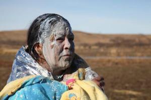 Tonya Stands recovers after being pepper sprayed by police after swimming across a creek with other protesters hoping to build a new camp to block construction of the Dakota Access Pipeline, near Cannon Ball, N.D., Wednesday, Nov. 2, 2016. Officers in riot gear clashed again Wednesday with protesters near the Dakota Access pipeline, hitting several dozen with pepper spray as they waded through waist-deep water in an attempt to reach property owned by the pipeline's developer. (AP Photo/John L. Mone)