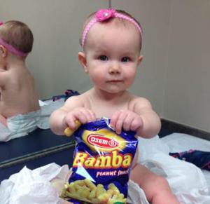 In this photo provided by the Carrie Stevenson, her daughter Estelle holds a bag of peanut snacks in her pediatrician’s office at age nine-months, in Columbus, Ohio. Most babies should start eating peanut-containing foods well before their first birthday, say guidelines released Thursday that aim to protect high-risk tots and other youngsters, too, from developing the dangerous food allergy. The new guidelines from the National Institutes of Health mark a shift in dietary advice, based on landmark research that found early exposure dramatically lowers a baby's chances of becoming allergic. (Carrie Stevenson via AP)