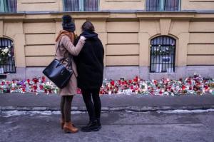 A survivor, right, is embraced by another girl as they stand at a makeshift memorial outside Szinyei Merse Pal Secondary School to pay tribute to victims of the crash of a Hungarian bus in Italy in Budapest, Hungary, Monday, Jan. 23, 2017. Hungary observes a day of national mourning after a bus carrying students of this secondary school from France back to Hungary crashed on a highway near Verona last Friday night killing  more than a dozen people.  (Bea Kallos/MTI via AP)