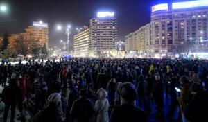 People stand in front of the government headquarters during protest against the government's plan to pardon thousands of prisoners through an emergency ordinance, in Bucharest, Romania, Wednesday, Jan. 18, 2017. Several thousand people marched through the Romanian capital on Wednesday night to protest the government's plan to pardon thousands of prisoners, a surprise move to allegedly reduce overcrowding in prisons that would also benefit some notable government supporters. (AP Photo/Andreea Alexandru)