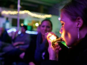 FILE - In this Dec. 31, 2012 file photo, Rachel Schaefer, of Denver, smokes marijuana on the official opening night of Club 64, a marijuana-specific social club, where a New Year's Eve party was held in Denver. Denver is starting work on becoming the first city in the nation to allow marijuana clubs and public pot use in places like restaurants, yoga studios and art galleries. Voters narrowly approved the "social use" measure last November. (AP Photo/Brennan Linsley, File)
