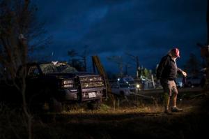 A member of the media walks near a truck that was damaged by an apparent tornado, Monday, Jan. 23, 2017, in Albany, Ga. A vast storm system kicked up apparent tornadoes, shredded mobile homes and left other destruction scattered around the Southeast over the weekend. (AP Photo/Branden Camp)