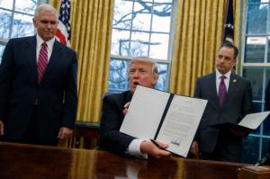In this Jan. 23, 2017, photo, Vice President Mike Pence, left, and White House Chief of Staff Reince Priebus watch as President Donald Trump shows off an executive order to withdraw the U.S. from the 12-nation Trans-Pacific Partnership trade pact agreed to under the Obama administration in the Oval Office of the White House in Washington. Trump’s "peace through strength" could mean more U.S. military power in Asia, reassuring allies about America’s resolve to counter China. That is, if they’re still looking to Washington for reassurance. Trump called his speedy withdrawal from the Trans-Pacific Partnership a victory for American workers hurt by multilateral trade pacts. (AP Photo/Evan Vucci)