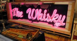 In this Friday, Jan. 20, 2017 photo, a marquee from the legendary Los Angeles rock 'n' roll club, Whisky a Go Go, glows at the Saco River Auction Co., in Biddeford, Maine. The sign that adorned the West Hollywood club during the heyday of punk, new wave and grunge in the 1980s and '90s, will go up for auction on Wednesday, Jan. 25. (AP Photo/David Sharp)