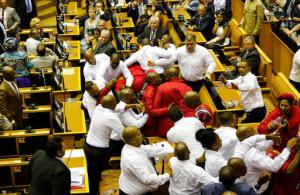 Economic Freedom Fighters in red are forcibly removed from parliament in Cape Town, South Africa, Thursday, Feb. 9, 2017. Parliament descended into chaos with opposition lawmakers denouncing President Jacob Zuma as a "scoundrel" and "rotten to the core" because of corruption allegations and then brawling with guards who dragged them out of the chamber. (AP Photo/Sumaya Hisham, Pool)