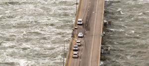 Vehicles sits on the road by a missing section of guard rail along a segment of the Chesapeake Bay Bridge-Tunnel where a tractor-trailer went over the southbound side at the 15-mile marker, Thursday afternoon Feb. 9, 2017, near Virginia Beach, Va. A truck driver died after heavy winds swept his tractor trailer off the 23-mile bridge-tunnel between Virginia Beach and the Delmarva Peninsula, and into the 45-degree, wind-swept waters below, authorities said. A Navy helicopter plucked a driver from the roof of the floating vehicle, but later died, authorities said. (Bill Tiernan/The Virginian-Pilot via AP)