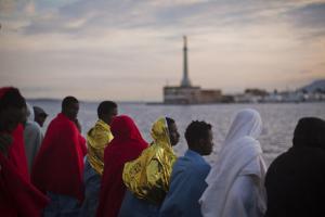 Wrapped in blankets, Sub-Saharan migrants look at the coast inside the Golfo Azzurro rescue vessel as they are arriving at the port of Messina, in Italy, with more than 299 migrants aboard the ship rescued by members of Proactive Open Arms NGO, on Sunday, Jan. 29, 2017. (AP Photo/Emilio Morenatti)