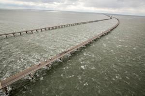 Vehicles sits on the road by a missing section of guard rail along a segment of the Chesapeake Bay Bridge-Tunnel where a tractor-trailer went over the southbound side at the 15-mile marker, Thursday afternoon Feb. 9, 2017, near Virginia Beach, Va. A truck driver died after heavy winds swept his tractor trailer off the 23-mile bridge-tunnel between Virginia Beach and the Delmarva Peninsula, and into the 45-degree, wind-swept waters below, authorities said. A Navy helicopter plucked a driver from the roof of the floating vehicle, but later died, authorities said. (Bill Tiernan/The Virginian-Pilot via AP)