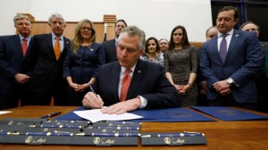 Virginia Gov. Terry McAuliffe, center, signs one of several bills relating to opioid addiction during a ceremony in the Patrick Henry Building in Richmond, Va., Thursday, Feb. 23, 2017. Looking on, from left, are Secretary of Public Safety and Homeland Security Brian J. Moran, Attorney General Mark Herring, Sen. Jennifer T. Wexton, D-Loudoun, Del. Dave A. LaRock, R-Loudoun, Del. Jennifer B. Boysko, D-Fairfax, Del. John M. O'Bannon III,, MD, R-Henrico, Ginny Atwood Lovitt, sister of heroin overdose victim Chris Atwood,, Del. Todd E. Pillion, R-Washington and others. (Bob Brown/Richmond Times-Dispatch via AP)