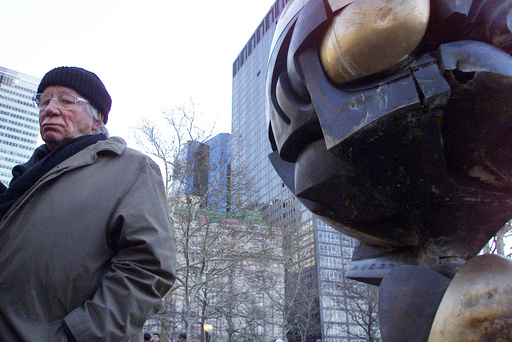 FILE - In this file photo dated Monday, March 11, 2002, German artist Fritz Koenig stands next to his bronze sculpture "The Sphere" after a dedication ceremony in New York.  Koenig who's artwork "The Sphere" became a symbol of resilience after the 9/11 attacks in New York, died Wednesday Feb. 22, 2017 aged 92, according to news reports and Bavaria state's Ministry of Culture. (AP Photo/Beth A. Keiser, FILE)
