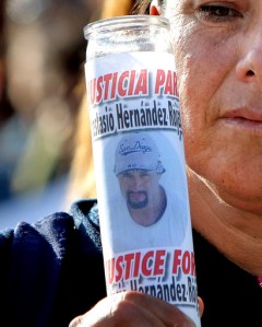 FILE - In this June 3, 2010 file photo, a woman holds a votive candle with an image of Anastasio Hernandez during a protest at the San Ysidro border crossing that separates Tijuana from San Diego, in Tijuana, Mexico. A federal judge tentatively approved an agreement Thursday, March 2, 2017, for the U.S. government to pay $1 million to the children of Hernandez, who died after being detained by immigration authorities and shot several times with a stun gun in 2010. The settlement is intended to end a nearly 7-year case that prompted widespread complaints that U.S. immigration authorities tolerated agents who use excessive force. (AP Photo, File)